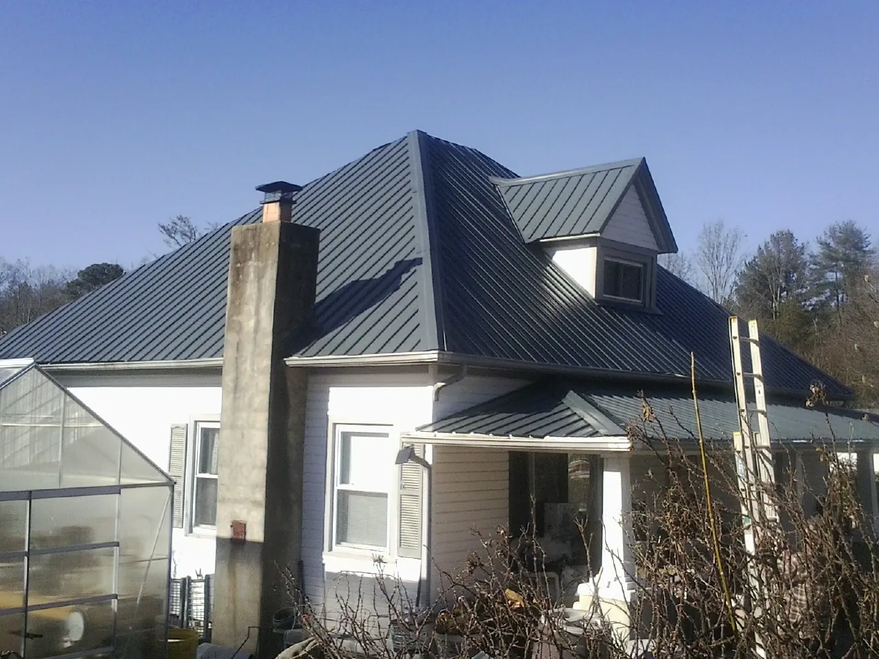 Dark blue standing seam metal roof on a white farmhouse with dormer — Slate & Tile Roof Repair by Roofing Brothers in Garnerville