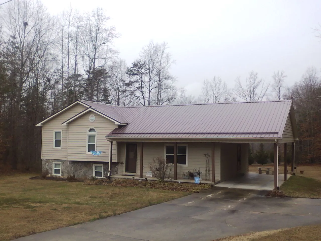 Burgundy metal roof on a tan split level home with an attached carport in Garnerville