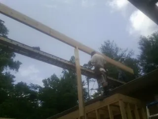 Carpenter setting a ridge beam over a new addition frame — Ice Dam Removal by Roofing Brothers in Garnerville