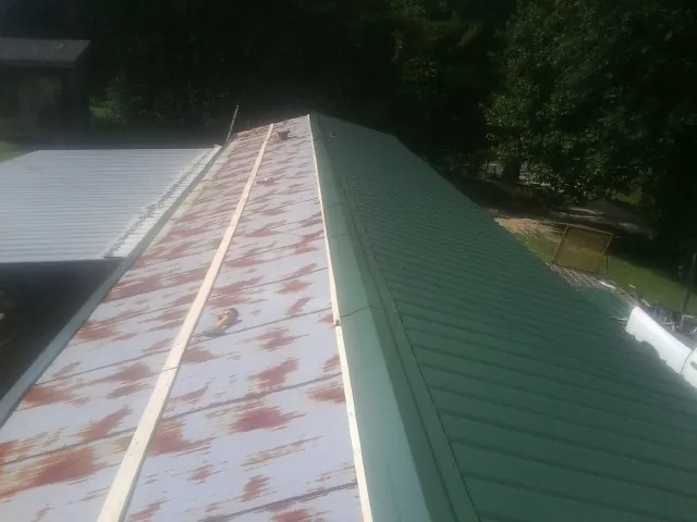 Old rusted panels beside newly installed green metal roofing — Wind Damage Roof Repair by Roofing Brothers in Garnerville