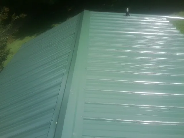 New green metal panels meeting at the ridge of a roof — Flat Roof Repair work by our crew in Garnerville