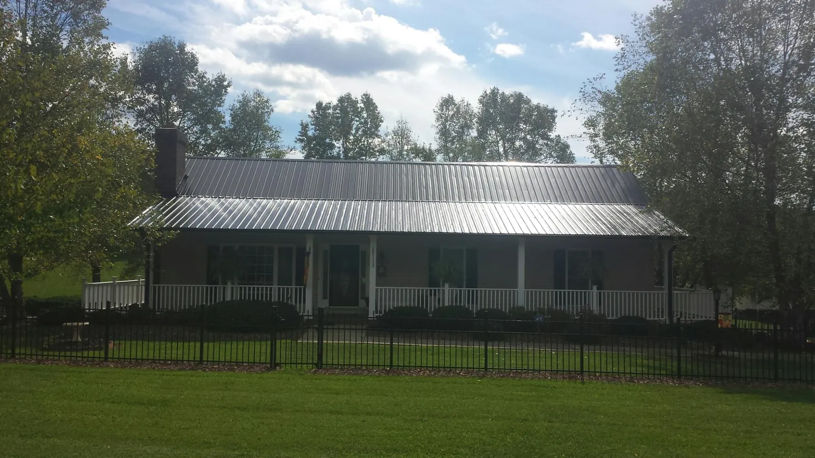 Gray metal roof on a brick ranch with a full width front porch — Gutter Guard Installation work by our crew in Garnerville