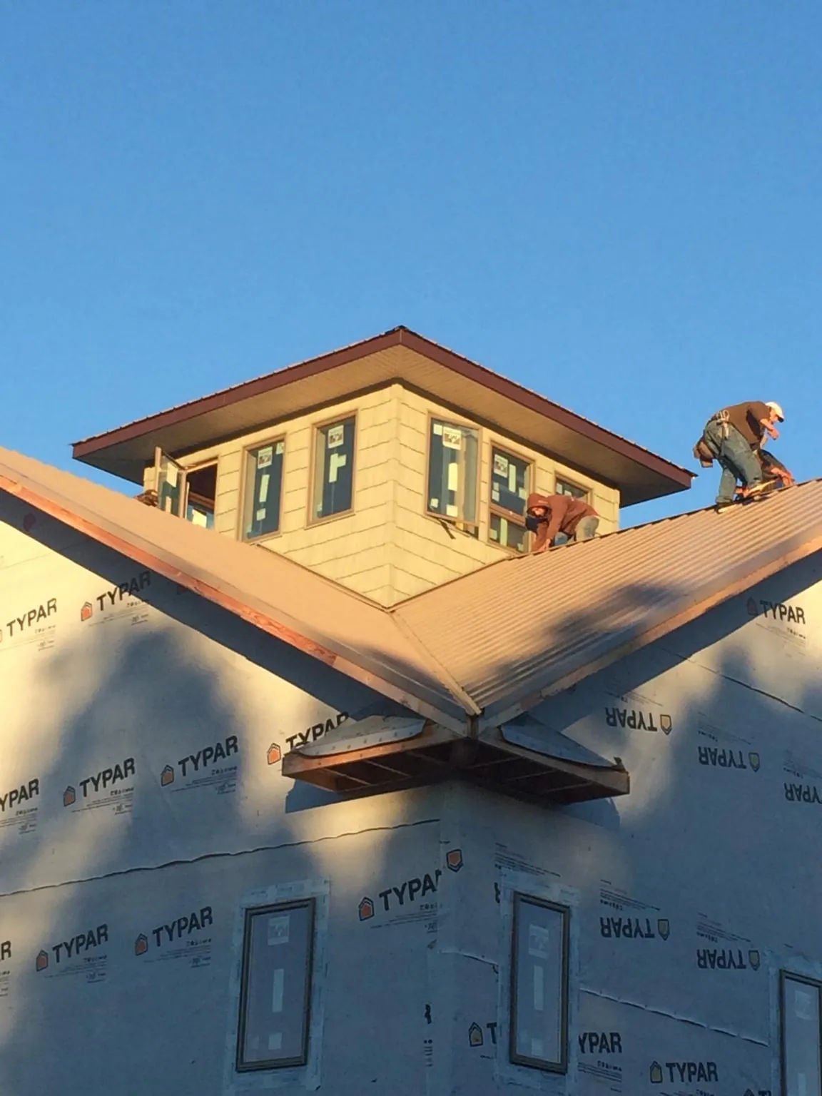 Roofers working around a rooftop cupola on a new metal roof at sunset — Roof Waterproofing in Garnerville by Roofing Brothers